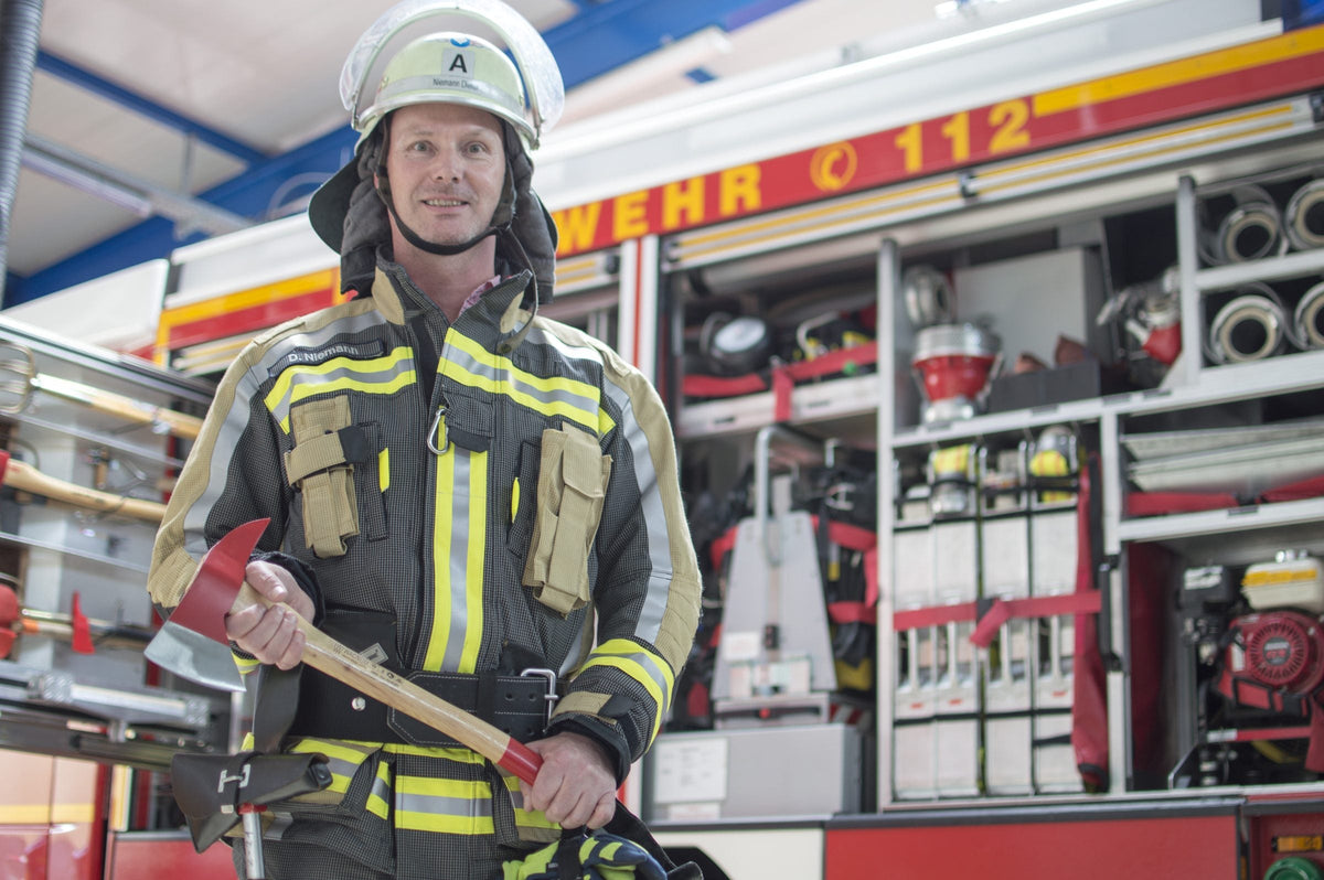 Feuerwehrmann mit WAGNUM Feuerwehraxt vor Löschfahrzeug