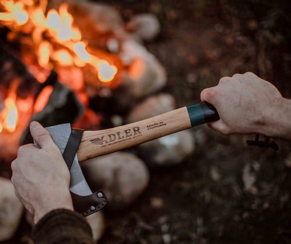 adler yankee hatchet held by to hands above a camp fire